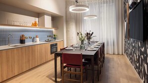 Eine moderne Küche mit Holzausziehtisch, einem Essbereich mit Tisch für vier Personen und einem großen Fenster mit Vorhängen.