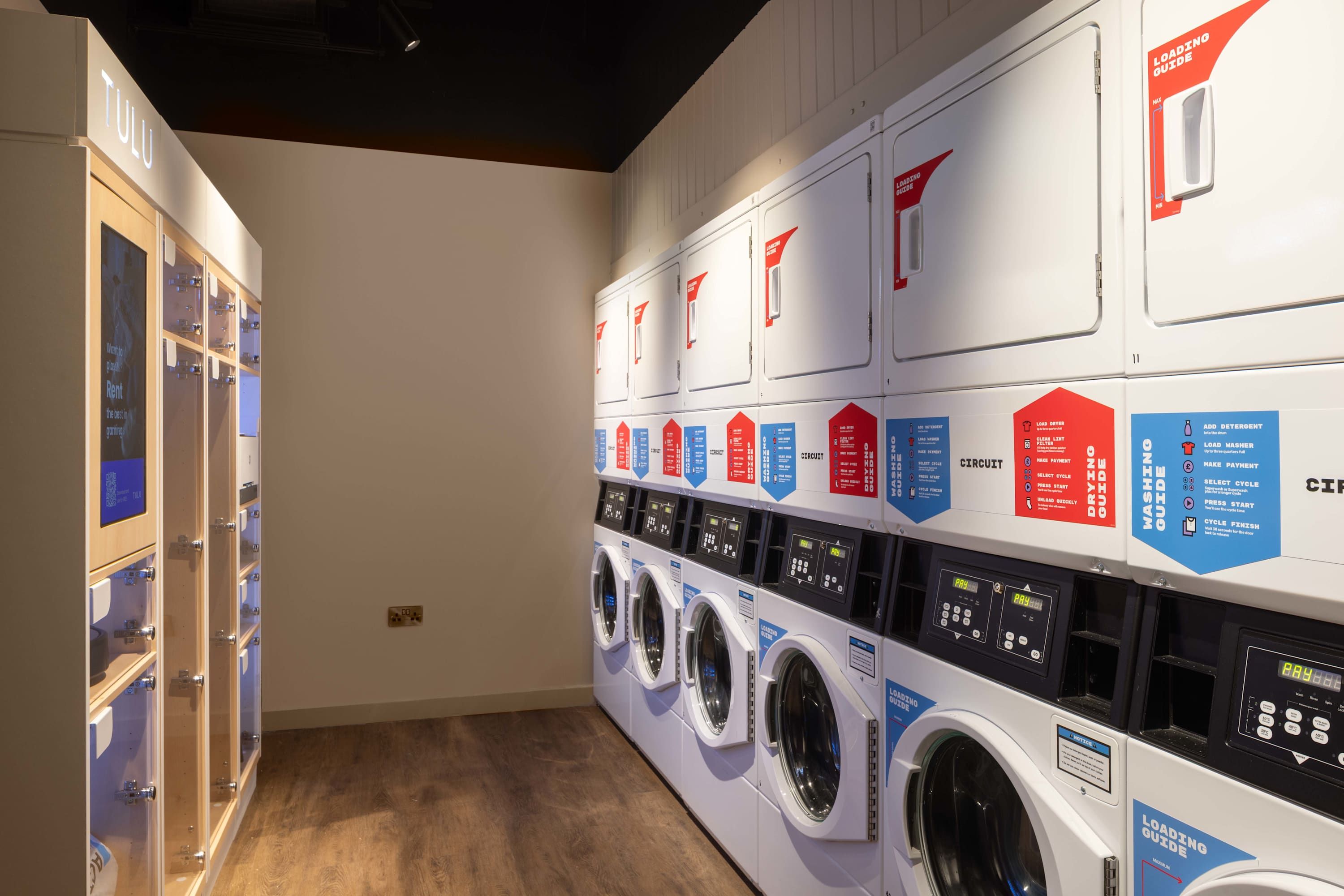 A laundry facility with multiple washing machines and dryers, each with instructional labels.