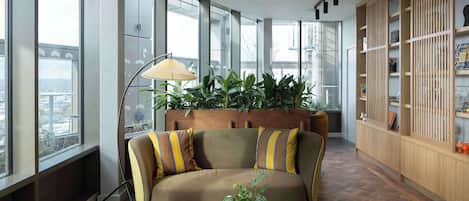 Ein stilvoller Lounge-Bereich mit einer Couch, einer Stehlampe, einem Blumentopf und einem Bücherregal.