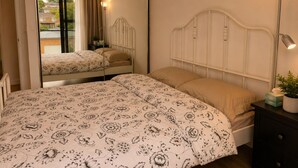 Un dormitorio con cama, mesita de noche, lámpara y espejo.