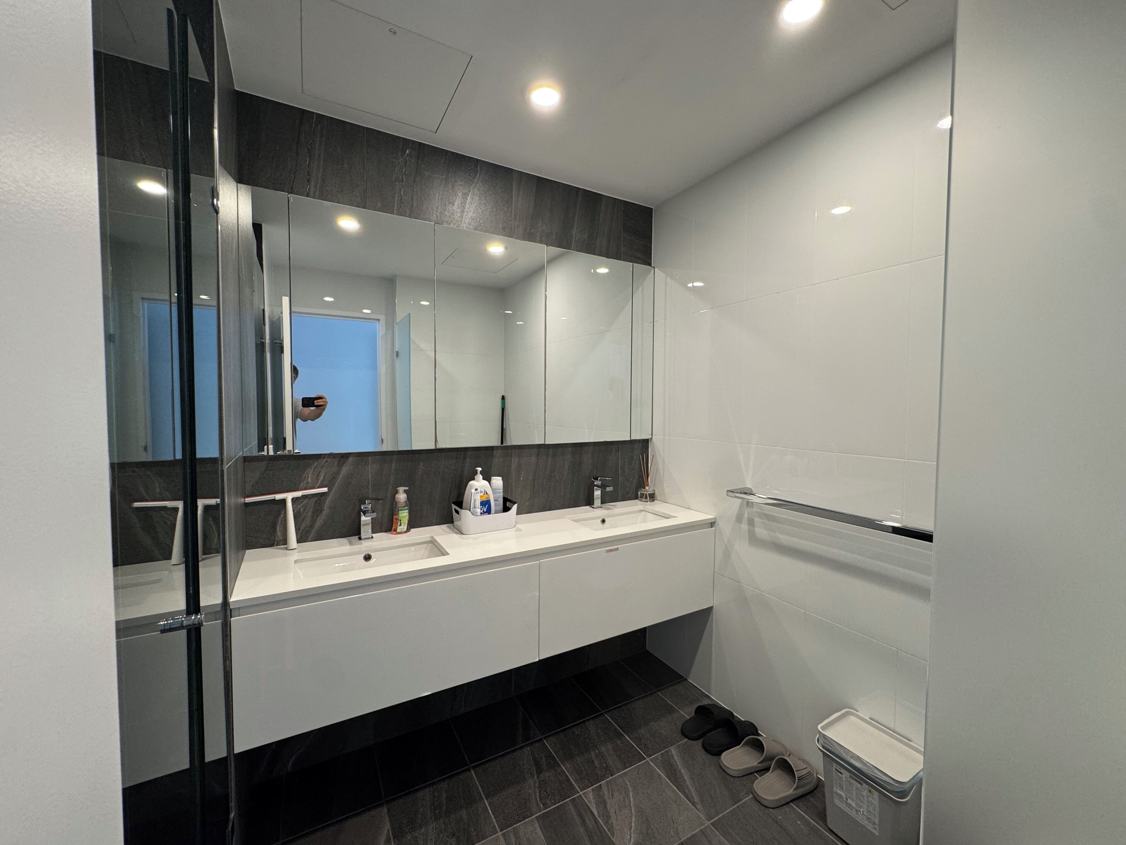 A modern bathroom with a glass shower enclosure, a double sink vanity, and a large mirror.