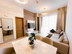 Ein modernes Wohnzimmer mit Esstisch, Sofa, Fernseher und einer Zimmerpflanze.