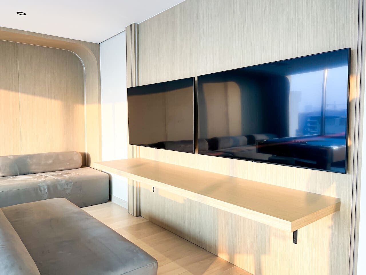 A modern interior with a built-in TV, a sofa, and a wooden accent wall.