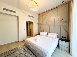 Ein modernes Hotelzimmer mit einem großen Bett, Nachttischen, einem integrierten Kleiderschrank und einem einzigartigen, geometrischen Wanddesign.
