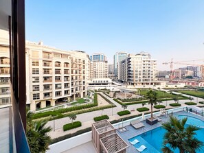 A residential building with multiple balconies, a swimming pool, and a landscaped courtyard. - Stylish 1-Bedroom Retreat in Prime Gardens | Arjan (Dubai)