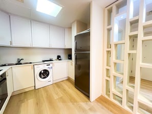 A compact kitchen with white cabinets, a stainless steel refrigerator, a washing machine, and a built-in oven. - Stunning 2BR In Dubai Marina With Amazing views (Dubai)
