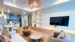 A modern living room with a flat-screen TV, comfortable seating, and a kitchen in the background. - Stunning 2BR In Dubai Marina With Amazing views (Dubai)