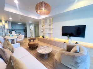 A modern living room with a flat-screen TV, comfortable seating, and a kitchen in the background. - Stunning 2BR In Dubai Marina With Amazing views (Dubai)