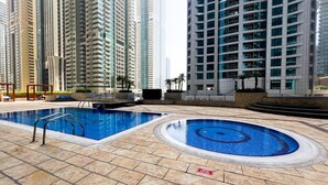 A swimming pool area with a diving board, surrounded by high-rise buildings. - Stunning 2BR In Dubai Marina With Amazing views (Dubai)