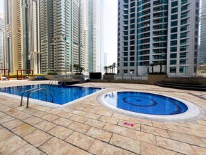 A swimming pool area with a diving board, surrounded by high-rise buildings. - Stunning 2BR In Dubai Marina With Amazing views (Dubai)
