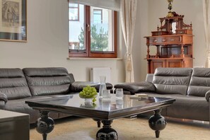 A modern living room with leather sofas, a glass coffee table, and a decorative wooden cabinet. - Belle Époque Suite by the Sea | 2 Bedrooms (Gdańsk)