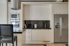 A modern kitchen with white cabinetry, a stainless steel refrigerator, a built-in oven, and a microwave. - Belle Époque Suite by the Sea | 2 Bedrooms (Gdańsk)