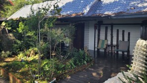 A traditional Japanese house with a tiled roof, a wooden deck, and a garden with various plants. - 清境禾風里湖畔農莊景觀餐廳適合登山騎行與家庭團體寵物友善 (Nantou County)