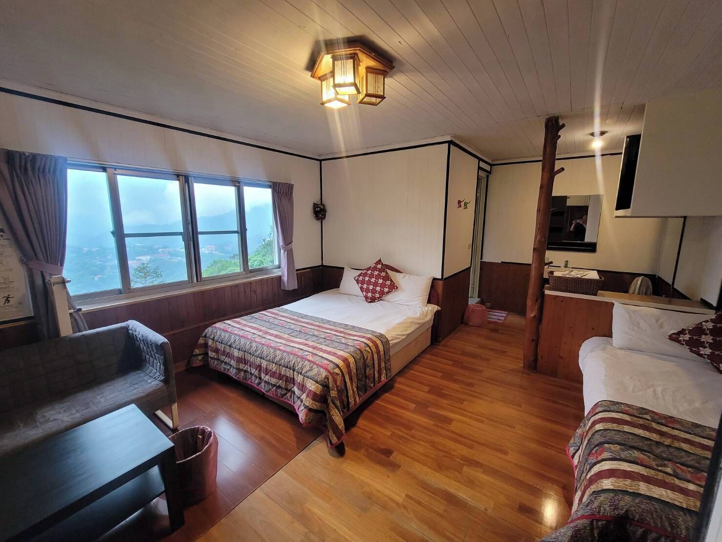 Una habitación con cama, escritorio, silla, mesita y ventana con vista.