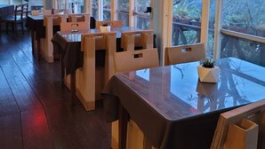 An indoor dining area with wooden tables and chairs, large windows, and hanging pendant lights. - 清境禾風里湖畔農莊景觀餐廳適合登山騎行與家庭團體寵物友善 (Nantou County)