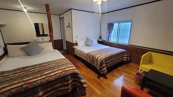 Een kamer met twee bedden, een houten vloer, een gele stoel en een raam met gordijnen.