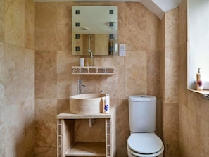 Ein Badezimmer mit freistehender Waschtischbecken, Toilette und Spiegel über dem Waschbecken.
