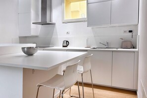 A modern kitchen with a white countertop, a kettle, a toaster, and a window above the sink. - URNEST Caldarese Charming 55sqm apartment under the Two Towers (Bologna)
