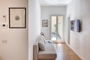 A hallway with a bench, framed artwork, and a door leading outside. - URNEST Caldarese Charming 55sqm apartment under the Two Towers (Bologna)