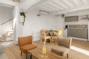 A modern kitchen with a dining area, wooden flooring, and a staircase. - Apt L’Hospital – In the heart of Tourrettes-sur-Loup (Tourrettes-sur-Loup)