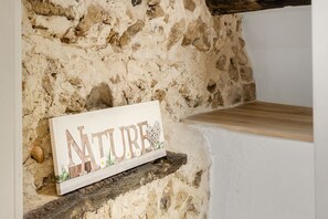 A rustic stone wall with a wooden shelf holding a sign that reads 'NATURE' with decorative elements. - Apt L’Hospital – In the heart of Tourrettes-sur-Loup (Tourrettes-sur-Loup)