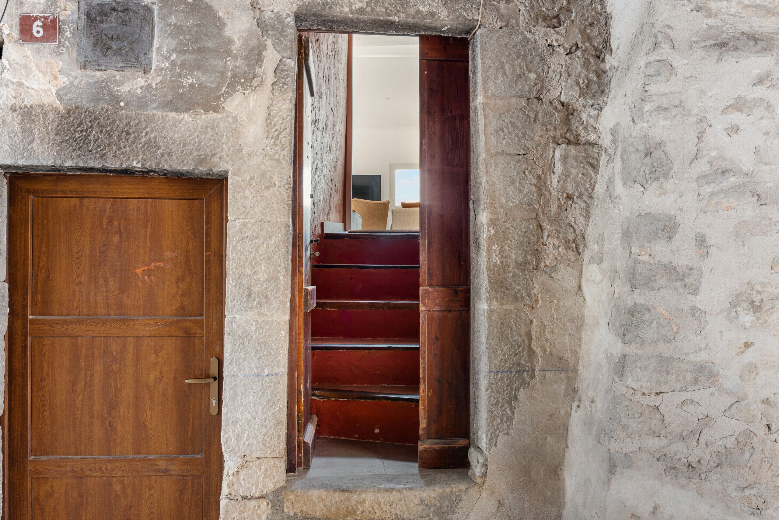 A stone building with a wooden door and a staircase leading to an upper level.