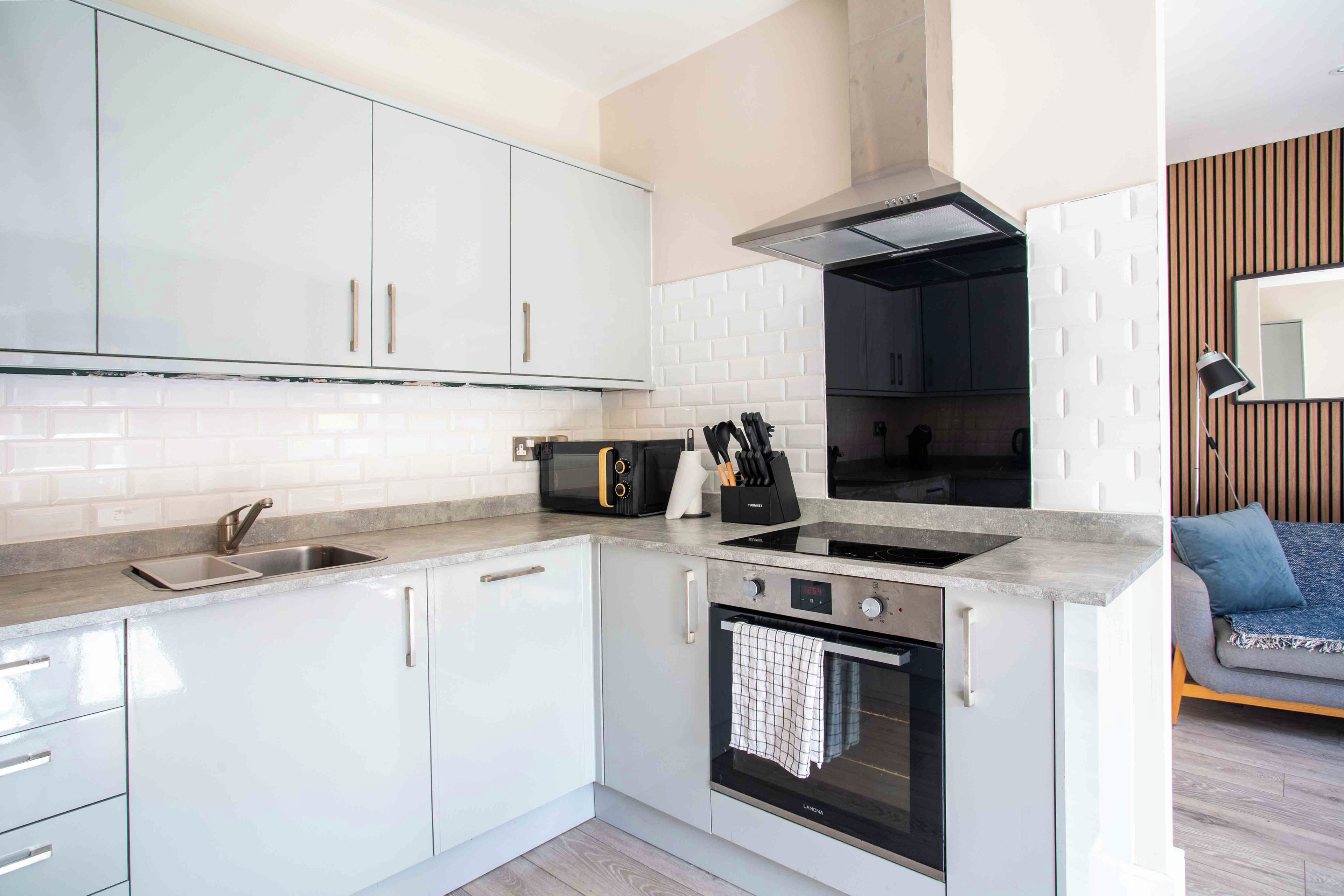 A modern kitchen with white cabinets, a built-in oven, a microwave, and a stove.
