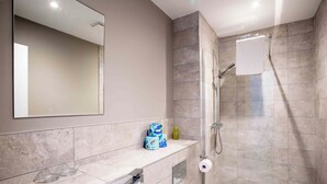 Un baño moderno con un espejo grande, una ducha y una bañera.
