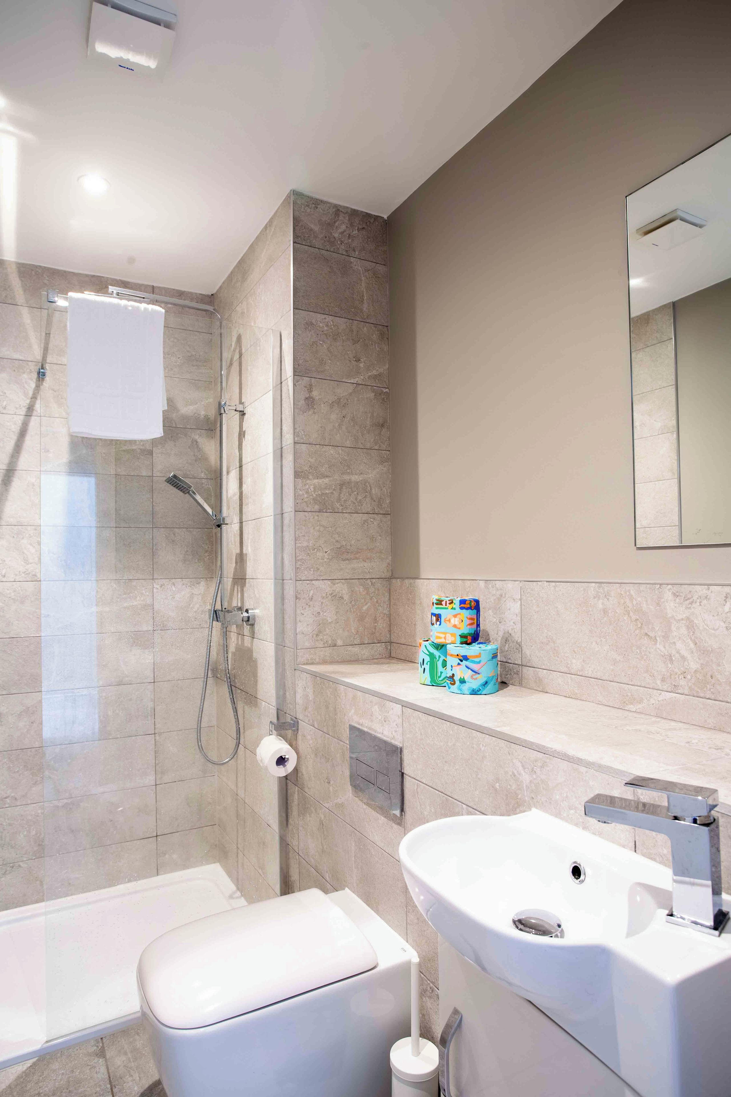 A modern bathroom with a shower, toilet, and sink.