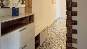 A hallway with patterned flooring, a wooden wall feature, and a white cabinet with drawers. - Mehrere Ferienwohnungen in Willingen (Willingen)