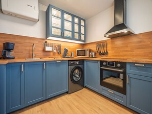 A modern kitchen with blue cabinets, a washing machine, a microwave, and a coffee maker. - Air-conditioned apartment with a garage and Wi-Fi (Le Grau-du-Roi)