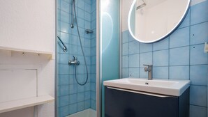 Ein Badezimmer mit Dusche, Waschbecken und Spiegel.