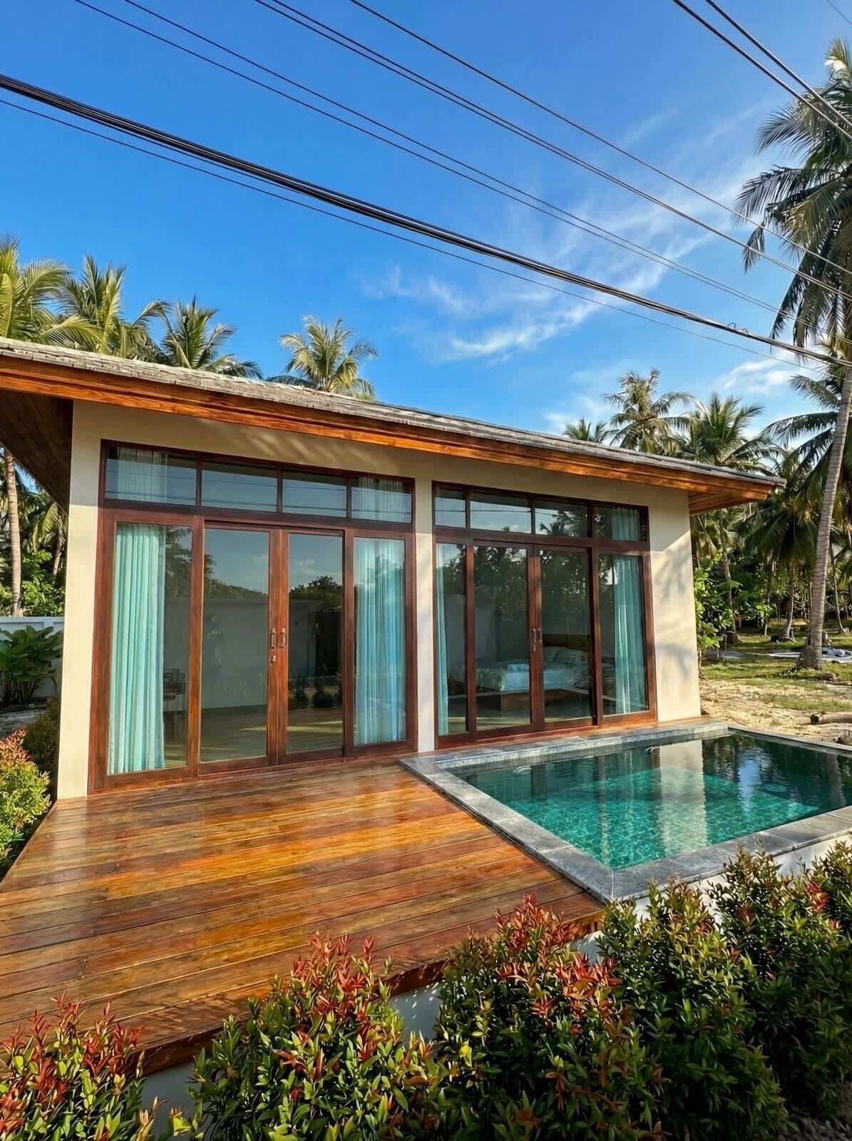 Una casa moderna con piscina, puertas de cristal amplias y una terraza de madera.