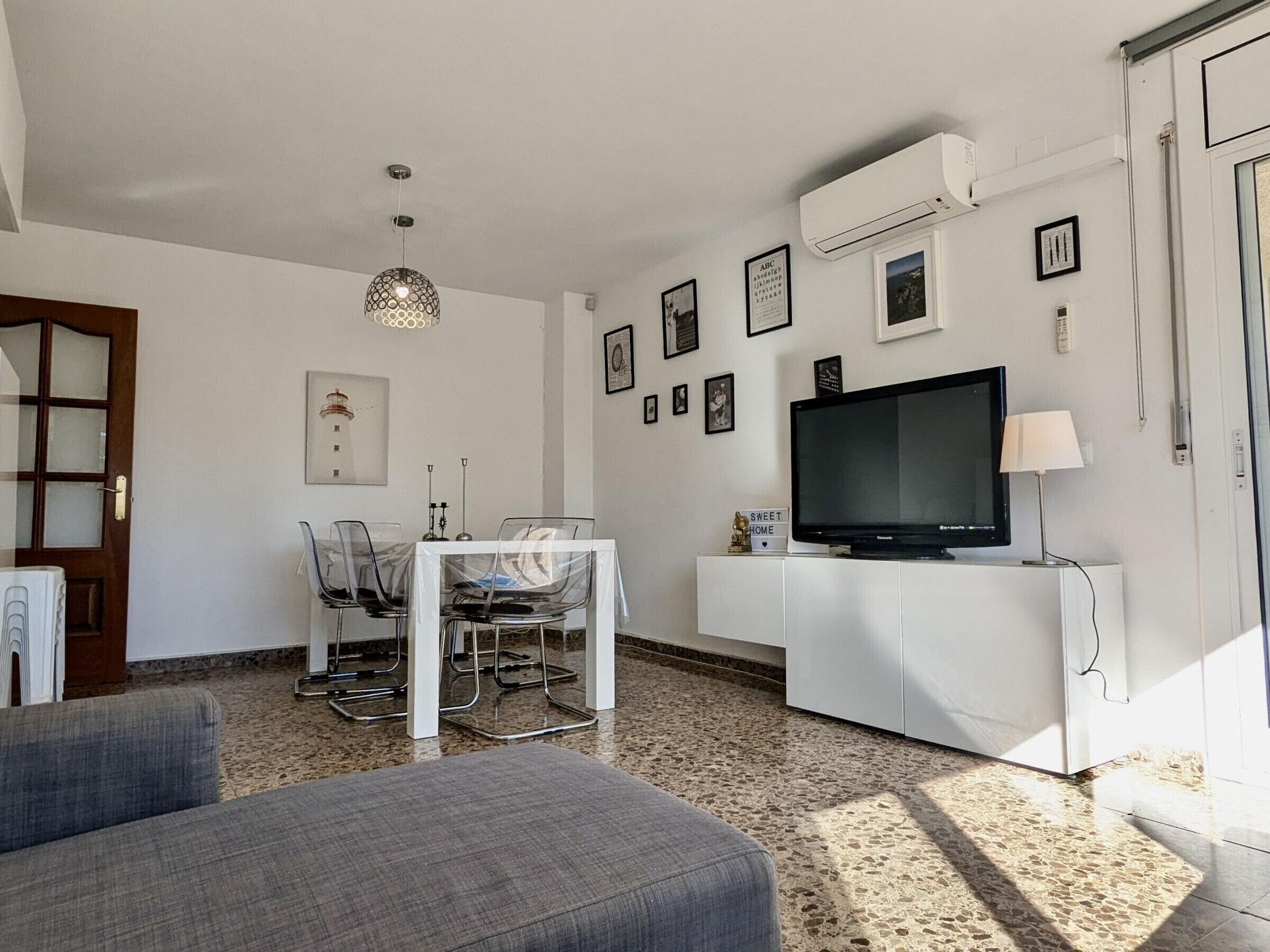 A living room with a television, a dining table with chairs, and a sofa.