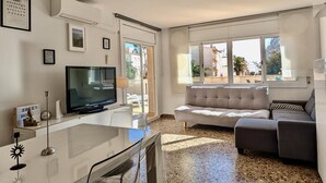 A modern living room with a flat-screen TV, a sofa, and a dining area with a glass table. - Spacious apt, pets welcome, central - 8 guests (Tossa de Mar)