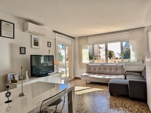 A modern living room with a flat-screen TV, a sofa, and a dining area with a glass table. - Spacious apt, pets welcome, central - 8 guests (Tossa de Mar)