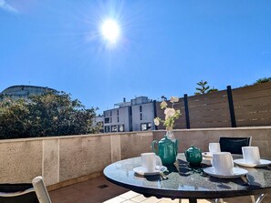 A round glass table with a white teapot, cups, and a vase with flowers on a balcony. - Spacious apt, pets welcome, central - 8 guests (Tossa de Mar)