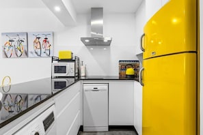 A modern kitchen with white cabinets, a yellow refrigerator, and a dishwasher. - Apartment with a Terrace and Swimming Pools in El Puerto (Estepona)