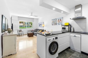 A modern kitchen with a built-in washing machine, a microwave, and a stove. - Apartment with a Terrace and Swimming Pools in El Puerto (Estepona)