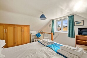 Ein Schlafzimmer mit Bett, Schreibtisch, Stuhl, Fernseher und Kleiderschrank.