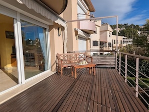 A wooden deck with a table and chairs, a glass door leading to a room, and a balcony with a railing. - House with private pool, parking - 8 guests (Tossa de Mar)