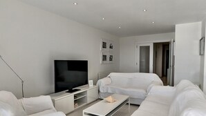 Una sala de estar moderna con una televisión de pantalla plana, un sofá, una mesita de centro y un mueble bajo.