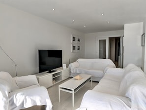 A modern living room with a flat-screen TV, a sofa, a coffee table, and a small cabinet. - Spacious apartment, panoramic view - 9 guests (Tossa de Mar)