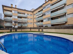 Un immeuble résidentiel avec une piscine en premier plan.