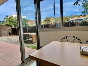 Ein Zimmer mit einem großen Fenster, einem Holztisch und einem Stuhl.