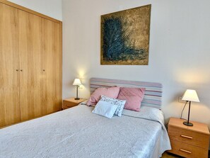 Ein Schlafzimmer mit einem Bett, zwei Nachttischen, einem Kleiderschrank und einem Bild an der Wand.