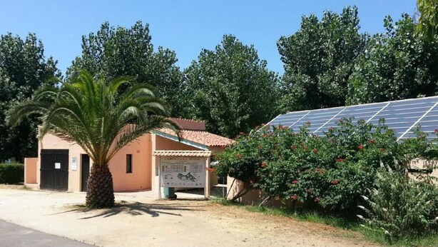 A building with a solar panel array, a palm tree, and a signboard. - Cozy bungalow, pets welcome - 4 guests (ALBITRECCIA)