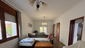 Una camera compatta con pavimento a motivi, un letto, un divano, un tavolino e un'area da pranzo con tavolo e sedie.