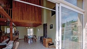 A spacious living area with a dining table, wooden furniture, and a sliding glass door leading to an outdoor patio. - Cottage, pets allowed, nature in Apinac - 12 guests (Apinac)