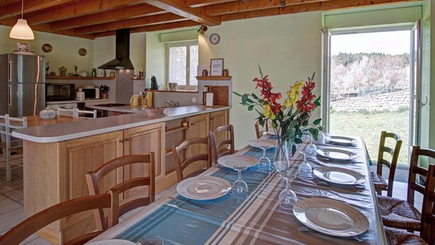 A kitchen with wooden beams, a dining area with a table set for six, and a view of a forested landscape. - Cottage, pets allowed, nature in Apinac - 12 guests (Apinac)